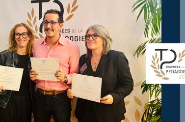Deux femmes et au milieu un homme enseignant tenant des diplômes dans la main et sont phographiés debout sur le côté nous voyons le logo du Trophée de la pédagogie