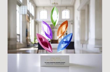 Trophée des 5 palmes de couleurs (bleu, orange, verte, violet, rose) Eduniversal derrière un fond blanc avec des colonnes