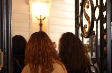 On voit les portes du Grand Amphithéâtre de la Sorbonne et plusieurs femmes de dos rentrer