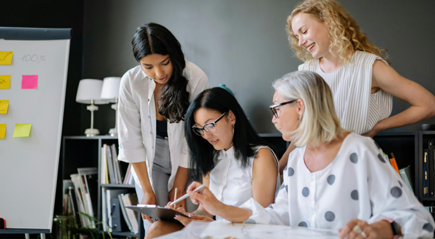4 filles autour d'un ipad qui travaille ensemble dans la bonne humeur