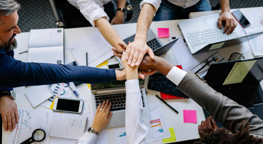 Plusieurs mains se joignent au-dessus d'une table pour montrer l'esprit d'équipe