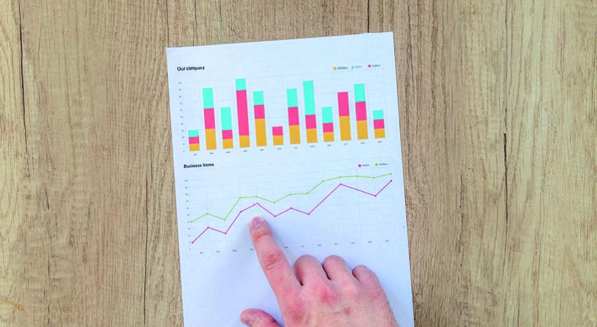 Doigt qui pointe une infographie avec des graphiques sur une table en bois