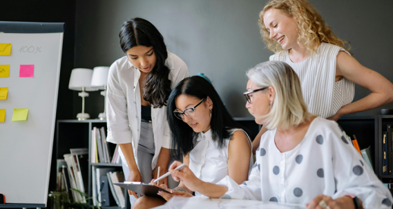 4 filles autour d'un ipad qui travaille ensemble dans la bonne humeur