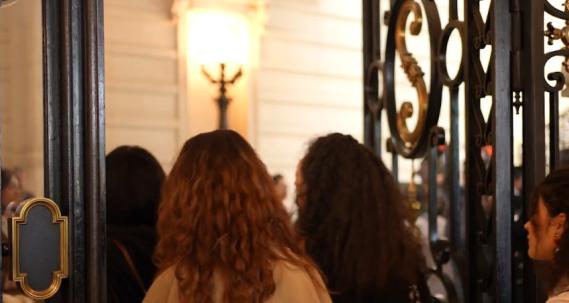 On voit les portes du Grand Amphithéâtre de la Sorbonne et plusieurs femmes de dos rentrer
